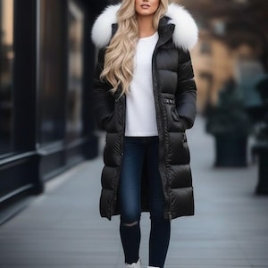 Peut inclure: Longue doudoune noire avec capuche bordée de fourrure blanche. Le manteau est porté sur un haut blanc et un jean bleu foncé. Des bottines blanches complètent la tenue. Vêtement d'extérieur d'hiver.