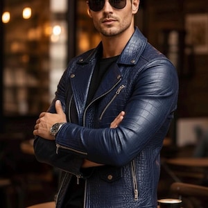 May include: A navy blue leather jacket with a crocodile pattern, featuring a zipper closure and silver hardware. The jacket is worn with a black shirt and sunglasses. A wristwatch is visible on the left wrist. The overall style is modern and fashionable.