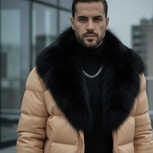 Puede incluir: Una chaqueta acolchada beige con cuello de piel negra y collar de cadena plateada. La chaqueta tiene cuello alto y cierre de cremallera. La persona lleva un cuello alto negro.