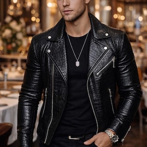 May include: Black leather jacket with a textured pattern, featuring a silver zipper and snap details. The jacket is paired with a black shirt and pants. A silver necklace and a watch complete the look. The jacket has a classic biker style.
