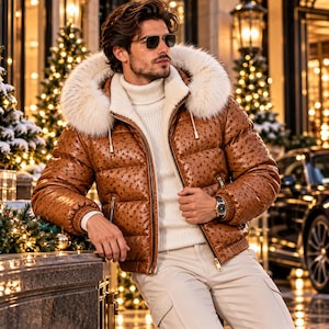 Puede incluir: Una chaqueta acolchada marrón con un patrón texturizado similar al avestruz, con una capucha grande forrada de piel sintética blanca, cierre de cremallera frontal y puños acanalados. Se lleva sobre un suéter de cuello alto blanco y pantalones claros.