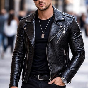 Pode incluir: Casaco de couro preto com padrão de pele de cobra, usado sobre uma camiseta preta e jeans pretos. O casaco tem fecho de zíper e um relógio prateado é visível no pulso. A pessoa está usando óculos de sol e um colar prateado.