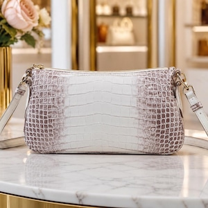 May include: A rectangular shoulder bag featuring a textured crocodile-embossed pattern with a gradient colour scheme transitioning from a white centre to light brown edges. The bag includes a top zip closure and a matching adjustable shoulder strap.