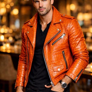 Puede incluir: Chaqueta de cuero naranja con un patrón texturizado, con un estilo motero clásico con cuello de solapa, cremallera asimétrica y múltiples bolsillos. La chaqueta tiene cremalleras y botones plateados. La persona lleva una camisa negra y vaqueros negros.