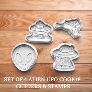 May include: A set of four white plastic cookie cutters and stamps in the shape of an alien head, a ray gun, and two UFOs. The text "SET OF 4 ALIEN UFO COOKIE CUTTERS & STAMPS" is printed below the cutters.