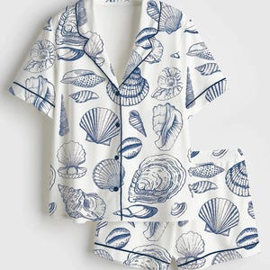 Könnte beinhalten: Ein Set aus drei Keramikbechern mit gesprenkelter, matter Oberfläche. Die Becher sind in Creme-, Hellgrau- und Dunkelgrautönen gehalten. Jeder Becher hat ein schlichtes, minimalistisches Design und einen abgerundeten Henkel.