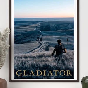 Könnte beinhalten: Gerahmter Druck mit einer Szene aus dem Film Gladiator. Das Bild zeigt eine Figur in Rüstung, die über eine weite Landschaft mit einer Straße blickt, die sich durch die Hügel schlängelt. Das Wort "GLADIATOR" ist unten in goldener Schrift dargestellt.