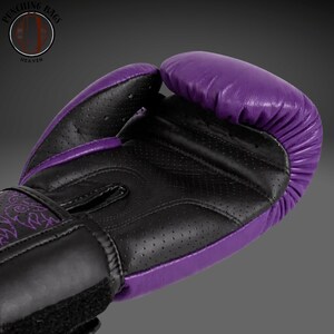 May include: A boxing glove featuring a vibrant purple and black color scheme. The palm area is constructed from black perforated material for ventilation, while the outer shell is smooth purple. A logo reading Punching Bags Heaven is visible.