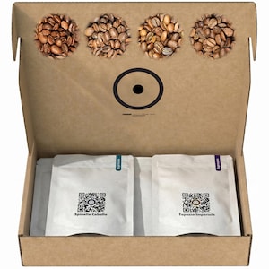 Könnte beinhalten: Ein brauner Karton mit vier kreisförmigen Ausstanzungen, die mit verschiedenen gerösteten Kaffeebohnen gefüllt sind. Darunter befinden sich zwei weiße Beutel mit der Aufschrift Espresso, QR-Codes sowie dem Text Spinello Cobalto und Topazio Imperiale.