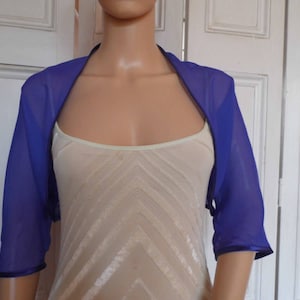 May include: A purple sheer bolero with short sleeves and a satin trim. The bolero is made of a lightweight fabric and is perfect for layering over a dress or blouse.