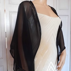 May include: A black sheer shawl with a satin trim. The shawl is draped over a white dress form.