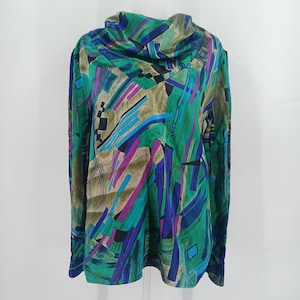 May include: A long-sleeve top featuring a cowl neckline and a vibrant abstract print in shades of emerald green, royal blue, magenta, and tan. The garment has a loose, flowing silhouette with straight sleeves and a straight hemline throughout.