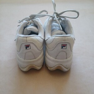 Puede incluir: Un par de zapatillas deportivas blancas con cordones blancos. Los zapatos tienen una suela gruesa y el logotipo de la marca es visible en la parte posterior de cada zapato. Los zapatos parecen ligeramente desgastados.