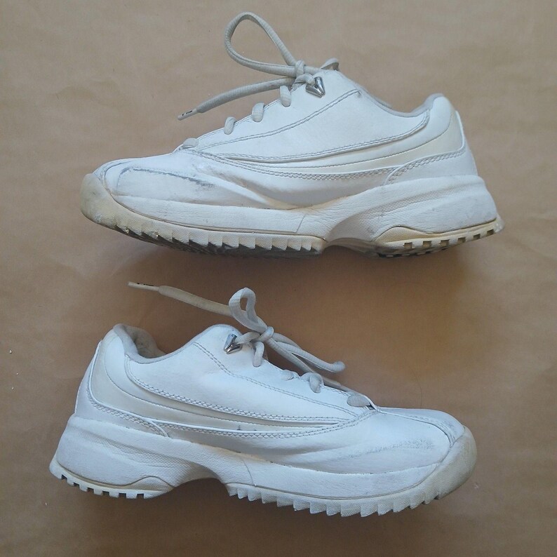 Puede incluir: Un par de zapatillas deportivas blancas con cordones. Las zapatillas tienen una suela gruesa y una banda de rodadura texturizada. Las partes superiores est&aacute;n hechas de un material liso con detalles cosidos. Las zapatillas parecen usadas.