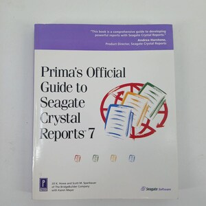 May include: A white paperback book titled Prima's Official Guide to Seagate Crystal Reports 7. The cover features a purple top banner with text, a red circular graphic with three stacked document icons, and small colored square icons at the bottom.