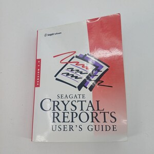 May include: A white and red Seagate Crystal Reports Version 5.0 user's guide manual. The cover features a graphic of a document with purple and black abstract lines and a red squiggle. The text reads Seagate Software, Version 5.0, and Crystal Reports.