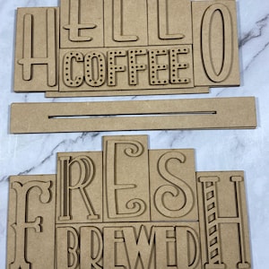 May include: Wooden sign with the words "Hello Coffee" and "Fresh Brewed" in a layered design. The letters are cut out and have a rustic look.