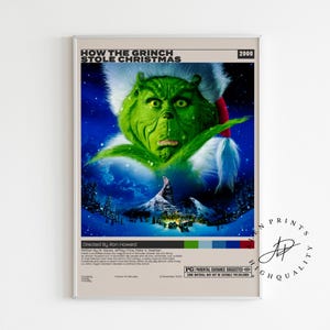 Puede incluir: Un póster enmarcado de la película "Cómo el Grinch robó la Navidad" (2000). El Grinch, una criatura verde con un cuello de piel blanca y detalles rojos, es el foco central. El póster tiene un fondo de escena invernal azul y blanco.