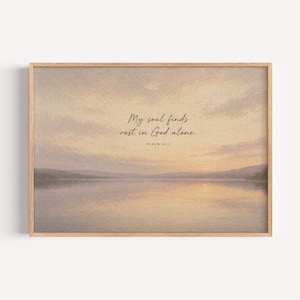 May include: A framed art print featuring a serene landscape with a lake and a sunset sky in soft pastel colors. The text "My soul finds rest in God alone. Psalm 62:1" is displayed in elegant script.