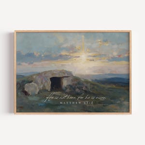 May include: A framed print featuring an artistic landscape with a stone structure and a bright sky. The artwork has a soft color palette of blues, greens, and yellows. The text "He is not there, for he is risen" is written on the print, along with "Matthew 28:6".