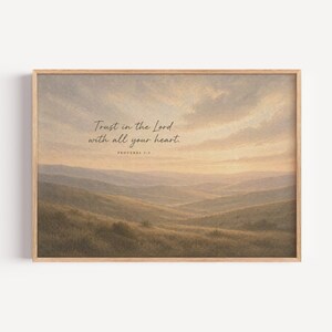 Puede incluir: Lámina artística enmarcada que representa un sereno paisaje montañoso bajo un cielo nublado. La obra de arte incluye el texto "Trust in the Lord with all your heart. Proverbs 3:5" en una escritura delicada, enmarcado en madera clara.
