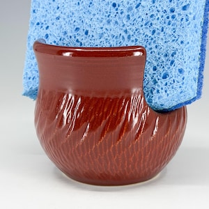 May include: A set of three ceramic mugs with a speckled, matte finish. The mugs are in shades of cream, light gray, and dark gray. Each mug has a simple, minimalist design and a rounded handle.