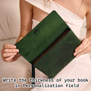 May include: Dark green leather book cover, open to reveal a book inside. The cover has a brown interior. Text at the bottom reads: "Write the thickness of your book in Personalization field."