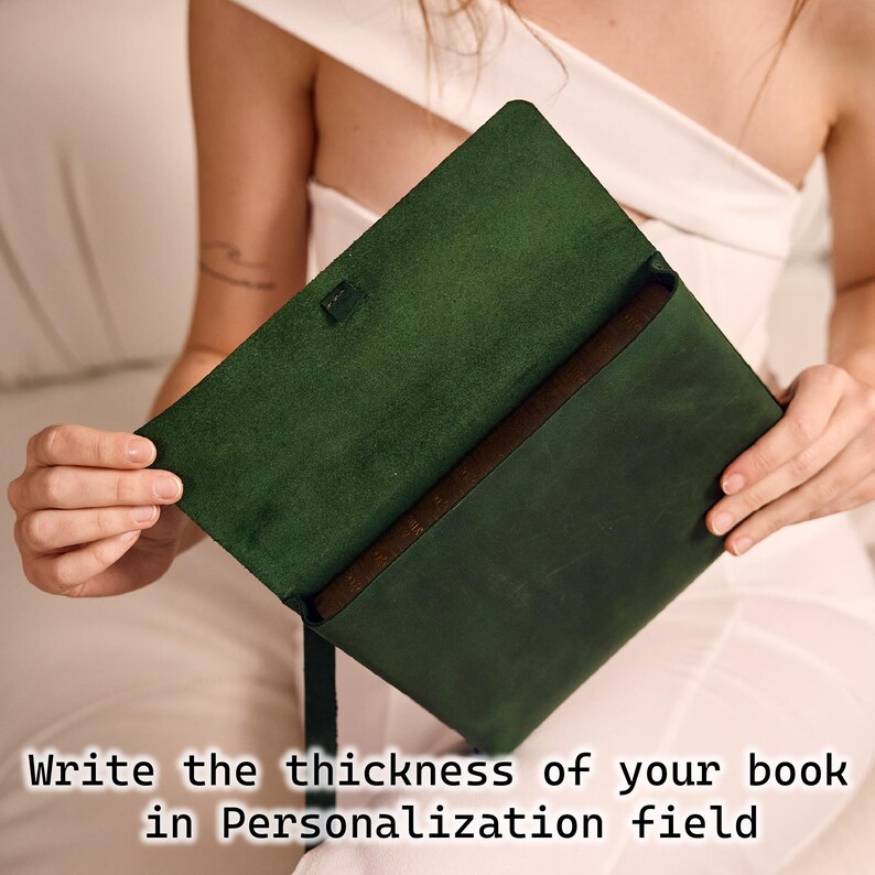 May include: Dark green leather book cover, open to reveal a book inside. The cover has a brown interior. Text at the bottom reads: "Write the thickness of your book in Personalization field."