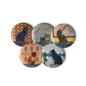 May include: A collection of five round cat-themed buttons. Each button features a different cat illustration against various patterned backgrounds, including geometric designs and scenic views. The cats are depicted in various poses and colors.