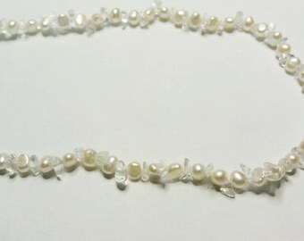May include: A white pearl and crystal necklace with a delicate and elegant design. The necklace is made of small, round pearls and clear crystal beads.