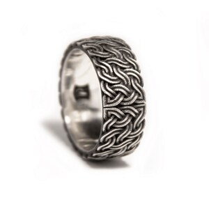 May include: A silver ring with a detailed, intricate woven design.
