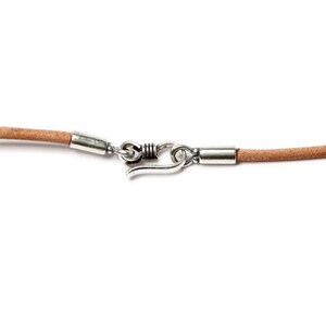 May include: A light brown leather cord necklace with silver metal clasps and a spring ring closure.