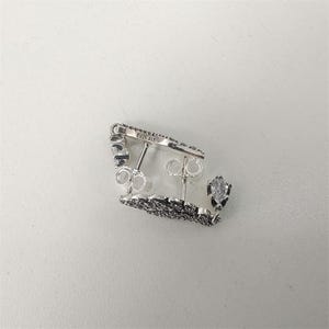 K&ouml;nnte beinhalten: Ein Paar silberfarbene Ohrringe mit floralem Design und kleinen, klaren Edelsteinen. Die Ohrringe haben einen Steckerverschluss und der Text "S925 ALE" ist sichtbar.