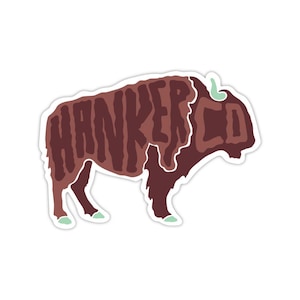 May include: A sticker featuring a bison silhouette in shades of brown and white. The word "HANKER CO" is written in a textured font across the bison's body. The bison has light green accents on its hooves and horns.