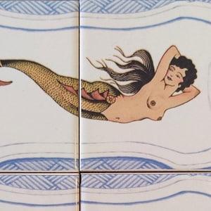 Puede incluir: Un conjunto de cuatro azulejos de cerámica cuadrados con una ilustración continua de una sirena con cabello oscuro y una cola dorada con escamas. El diseño incluye un borde azul y blanco a lo largo de los bordes superior e inferior.