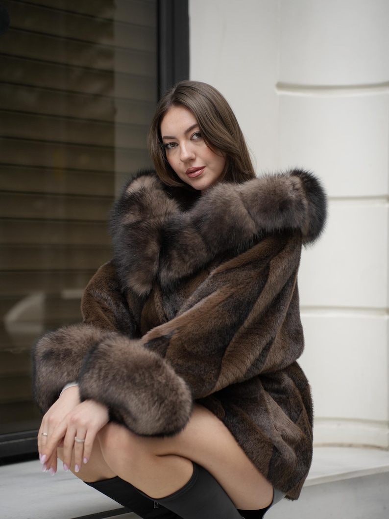 May include: A brown fur coat with a large collar and cuffs. The coat has a luxurious appearance and a rich, dark brown color. The fur appears soft and plush, suggesting warmth and comfort. The coat is a statement piece.