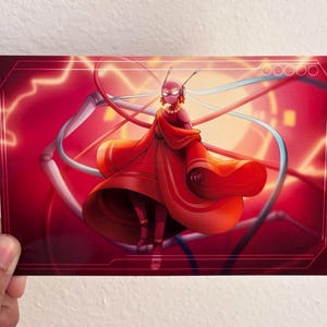 Op de afbeelding: Een levendige illustratie van een figuur in een vloeiende rode jurk, tegen een rode en oranje achtergrond met witte en blauwe lijnen. De figuur heeft een hoofd met antennes en een rood gezicht. Het kunstwerk staat op een rechthoekige kaart.