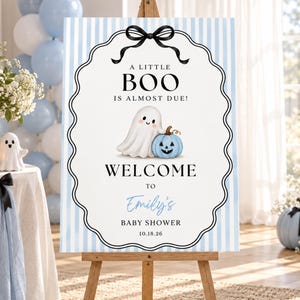 Puede incluir: Un letrero rectangular de bienvenida para baby shower con fondo de rayas verticales azul claro y blanco. El texto dice A LITTLE BOO IS ALMOST DUE, WELCOME TO Emily's BABY SHOWER 10.18.26, con una ilustración central de un fantasma y calabaza.