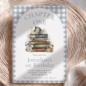 May include: An invitation with a light blue and white gingham border. The text "Chapter One" is above a stack of books and a small bear illustration. The invitation announces "Jonathan's 1st Birthday" with event details. Floral accents and an arch complete the design.