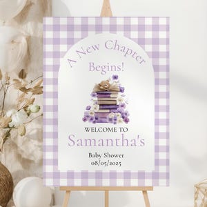 Puede incluir: Un letrero de bienvenida para baby shower con un borde de cuadros vichy lila. El letrero presenta el texto "A New Chapter Begins!" encima de una pila de libros, un oso de peluche y flores. Da la bienvenida a los invitados a la baby shower de Samantha el 08/05/2025.
