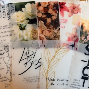 May include: A collection of translucent planner inserts with floral and inspirational designs. Some inserts feature text like "Lady Boss," "Think Positive," and "Simplicity." The inserts are decorated with roses, orchids, and other flowers.