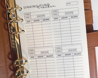 Puede incluir: Una carpeta de cuero marrón con herrajes dorados contiene una hoja de papel blanca. El inserto es un "Sinking Fund Tracker" con secciones para el fondo, el objetivo, la fecha de vencimiento, la fecha, la cantidad y el saldo. El texto es negro.