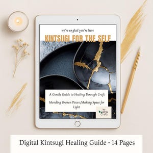 Puede incluir: Una tableta digital muestra una guía de curación Kintsugi titulada "Kintsugi for the Self". La guía presenta imágenes de cerámica negra con detalles dorados. También hay una vela, un bolígrafo y una ramita decorativa.