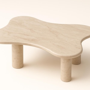 May include: A beige, organically shaped coffee table with three cylindrical legs. The tabletop has a unique, flowing design with a marbled texture. The table is made of stone and is suitable for living rooms.