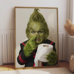 May include: A framed portrait of a green, furry creature with a pointed hairstyle, wearing a black jacket with red stripes. The creature is holding a roll of white toilet paper in one hand and touching its nose with the other furry green hand.