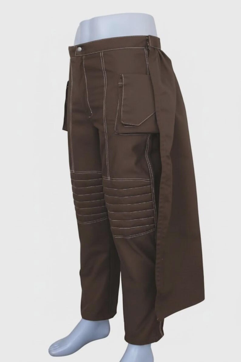May include: Brown pants with white stitching and a unique design. The pants feature multiple pockets and quilted knee panels. A long, flowing panel extends from the waist. The pants are displayed on a mannequin.