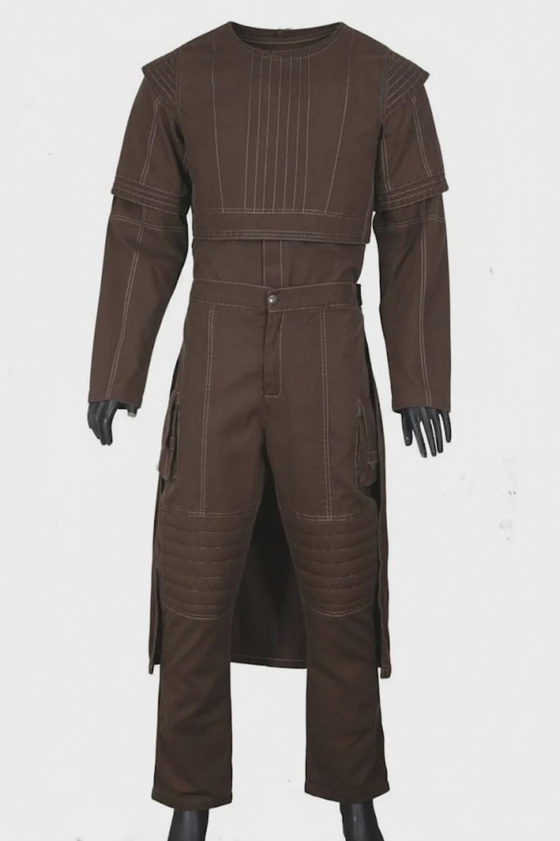 May include: Brown two-piece outfit with white stitching. The top has a crew neck and a layered design. The pants have cargo pockets and quilted knee pads. The outfit is a solid brown color.
