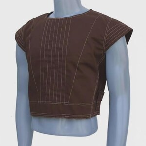 May include: A brown, sleeveless top with white stitching details. The top has a round neckline and a cropped hem. Vertical stitching runs down the center of the front. The garment is displayed on a mannequin.