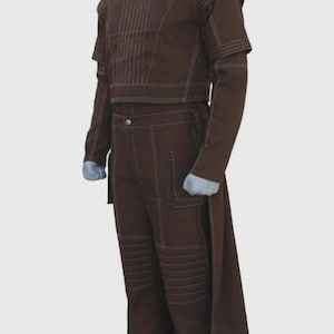 May include: A brown two-piece outfit with white stitching details. The top is a cropped, long-sleeved design with vertical stitching. The pants are high-waisted with pockets and knee panel stitching. A long, flowing panel extends from the back.