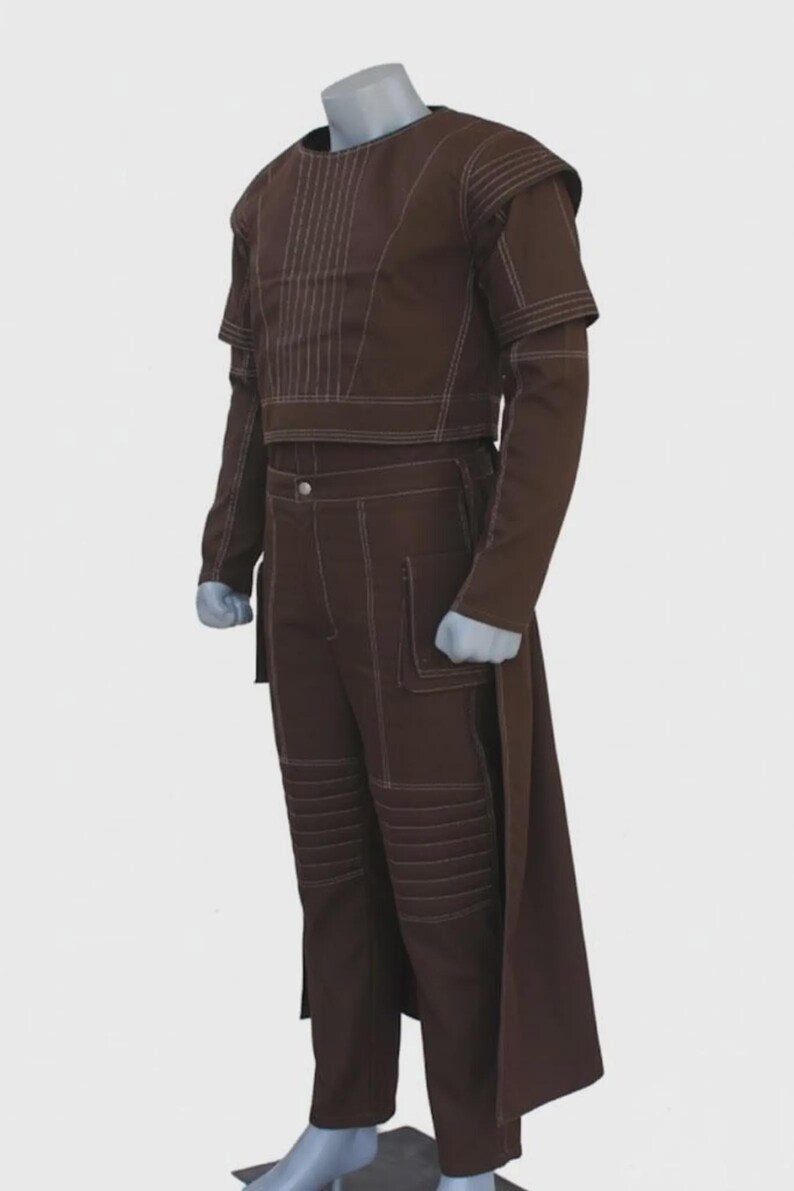 May include: A brown two-piece outfit with white stitching details. The top is a cropped, long-sleeved design with vertical stitching. The pants are high-waisted with pockets and knee panel stitching. A long, flowing panel extends from the back.